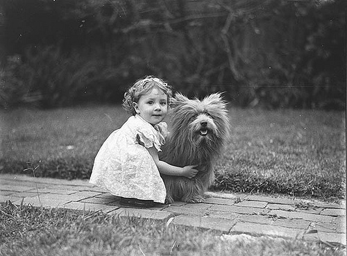 Old photo of a little girl hugging a small dog